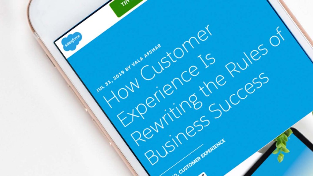 A phone displays a Salesforce article on how the customer experience is rewriting the rules of business success.