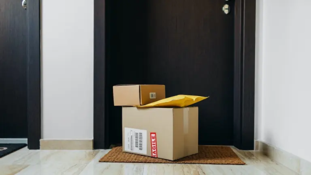 Three packages on the ground in front of a black door.