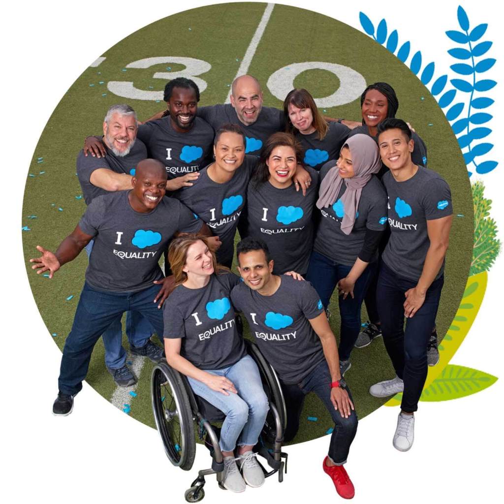 Group of people, some with visible disabilities, wearing a11y shirts posing on football field.